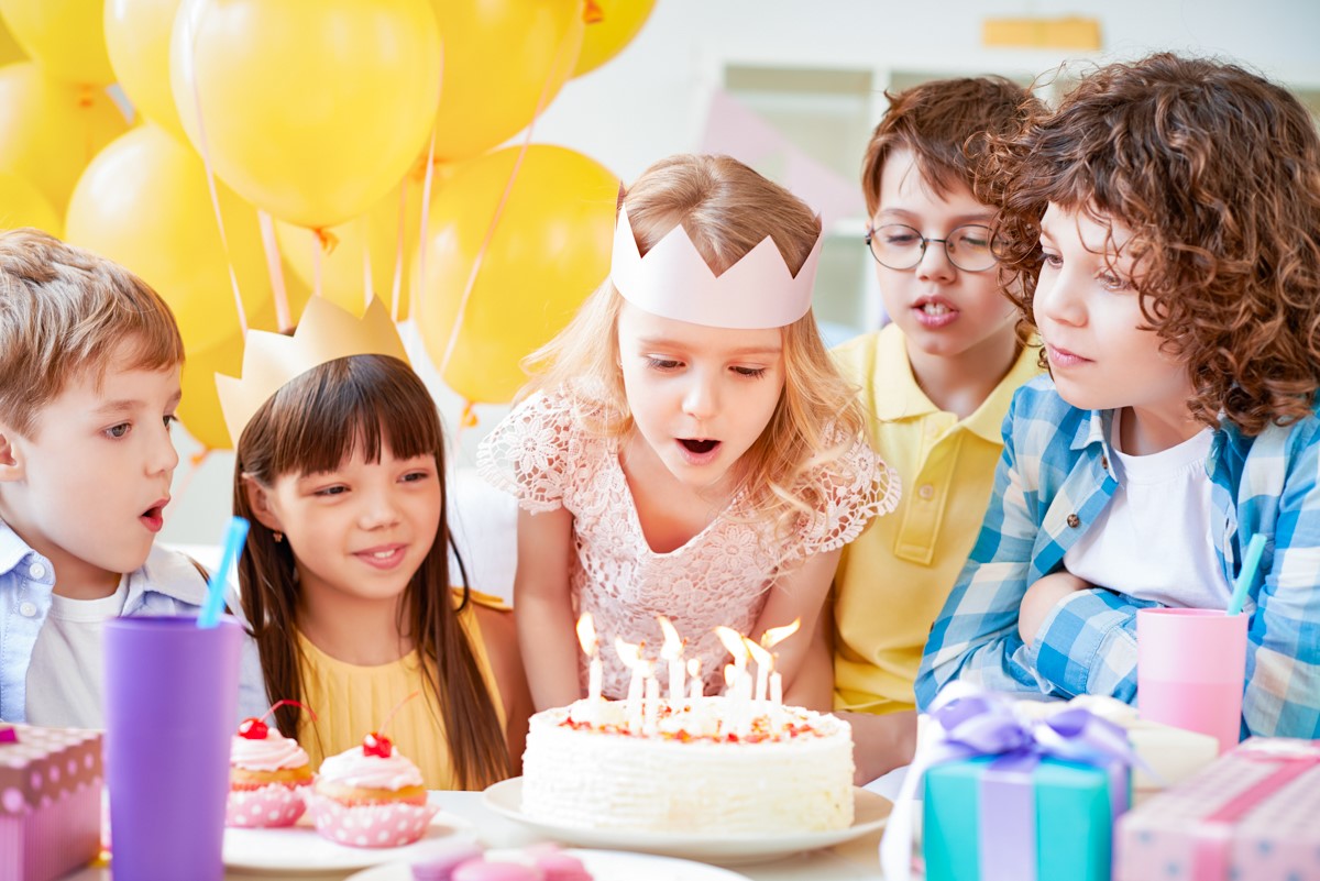 Kinder feiern gemeinsam einen Geburtstag mit Geburtstagskuchen, Kerzen, Luftballons und bunten Partydekorationen im Monki Park.